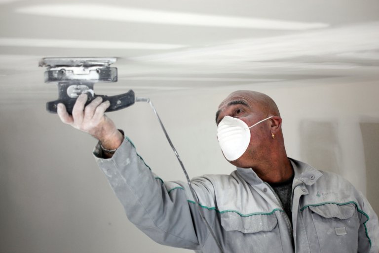 Man putting up a plasterboard ceiling